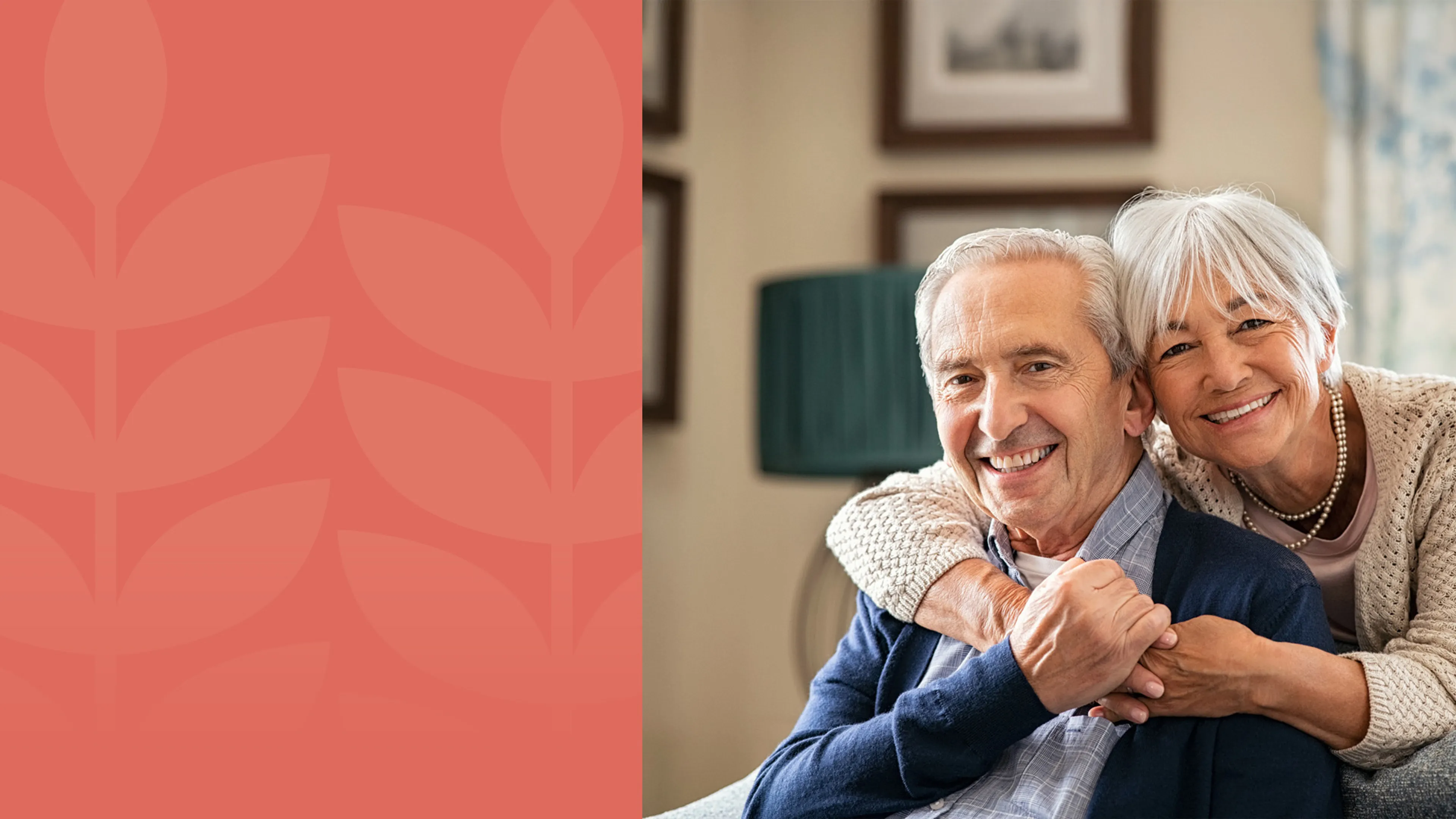 A gentleman is sitting on a couch in a contemporary home. Standing behind him is an older woman who is embracing him with her hands around his shoulders.