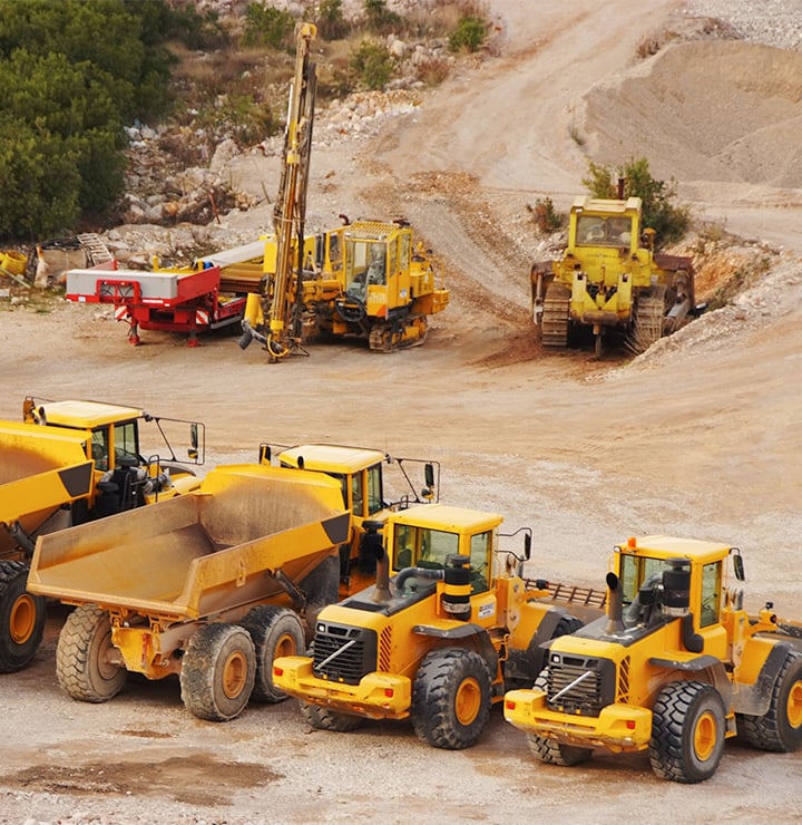 Heavy construction vehicles and equipment in a work yard.