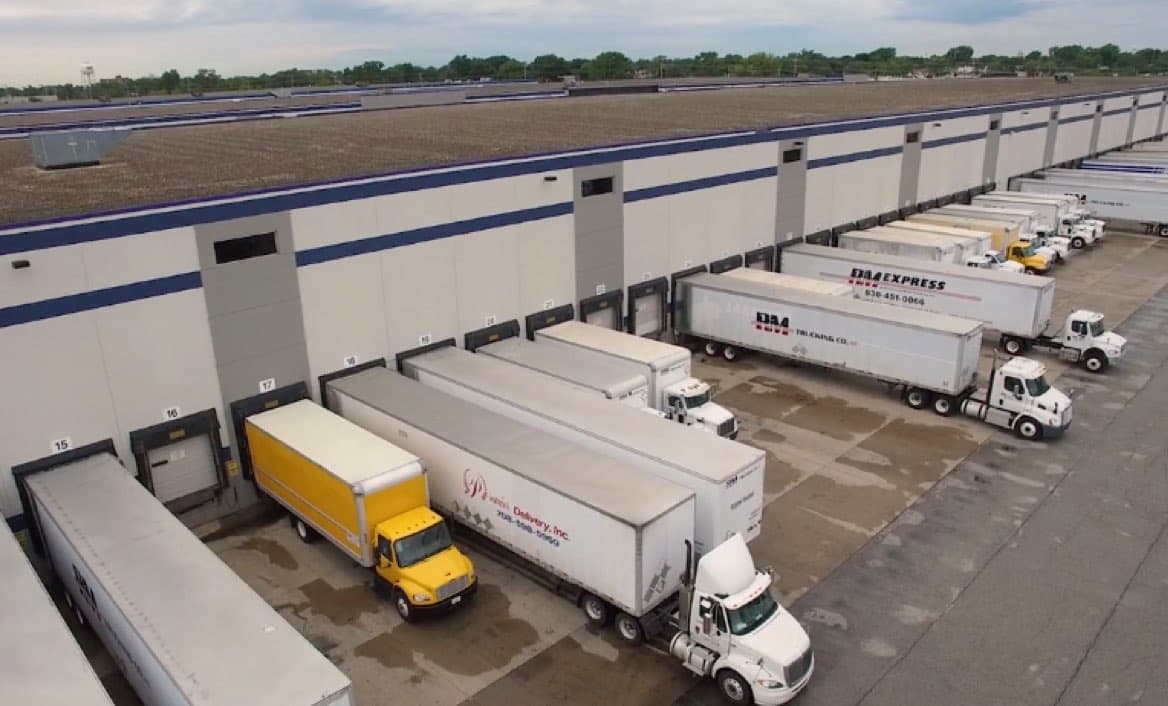Overhead view of a warehouse loading dock with many semi-trucks.