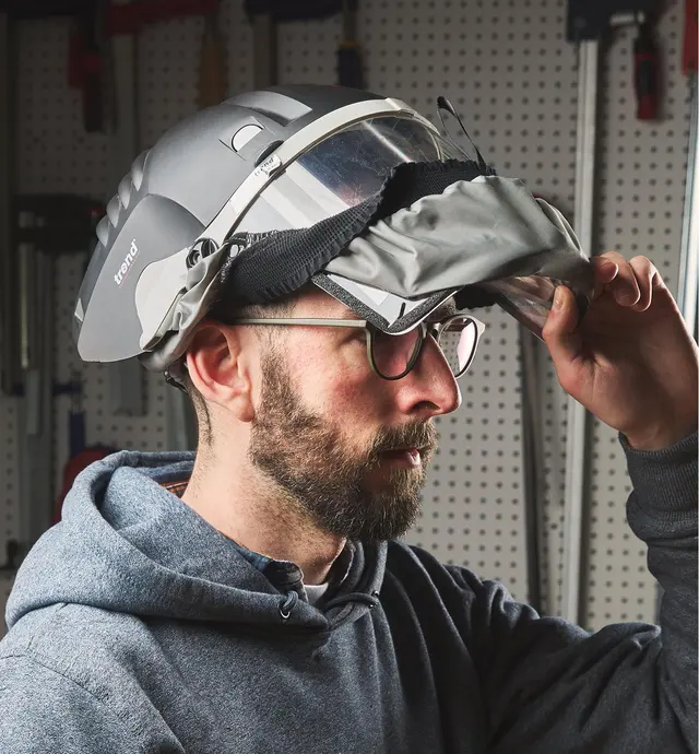 A person wearing a full-face shield and raising the visor
