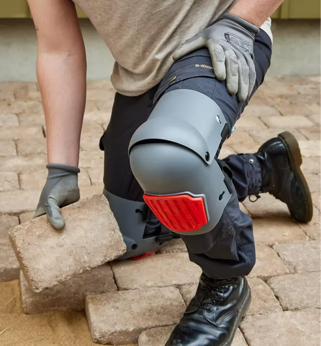 Patio stones being laid by a person wearing articulated knee pads