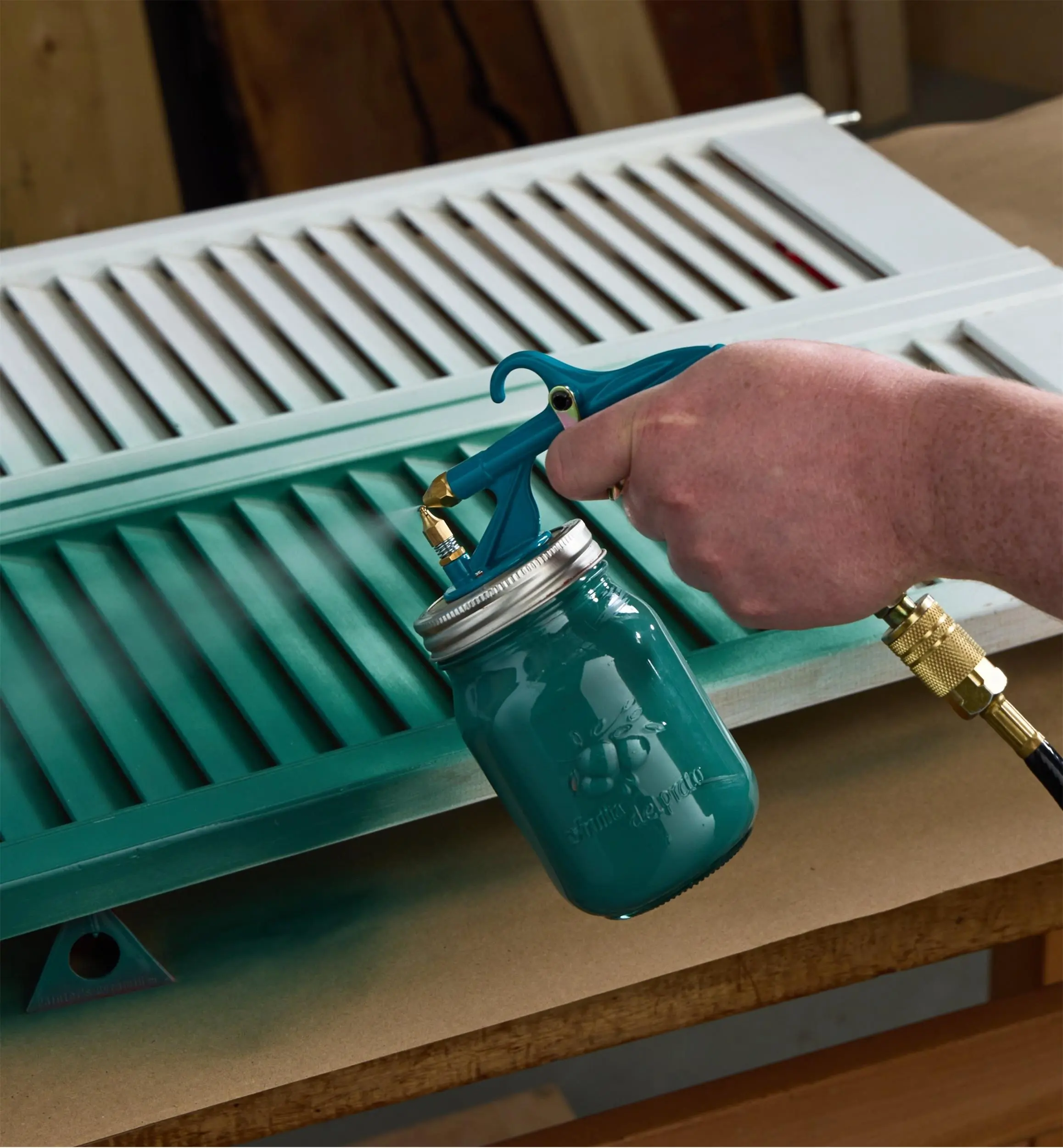Green paint being sprayed onto shutters using the Air-Powered Spray Gun