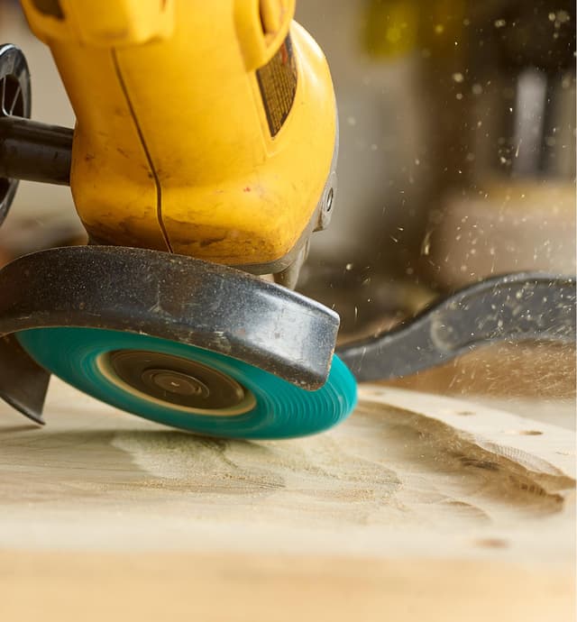 An angle grinder with a sanding disc being used to grind out a chair seat