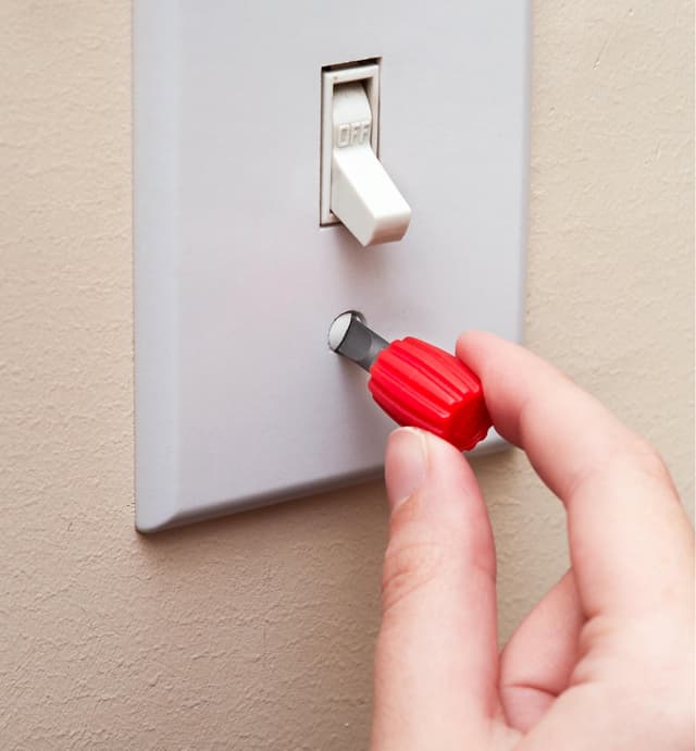 Serrage d'une vis d'une plaque d'interrupteur avec un mini porte-embout