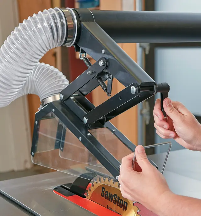 The dust collection guard being adjusted for height to suit stock thickness