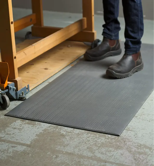 Personne debout sur un tapis anti fatigue devant un établi