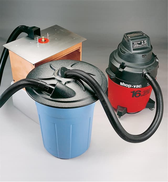 Cyclone lid on a garbage pail connected by hoses between a router table and a shop vac
