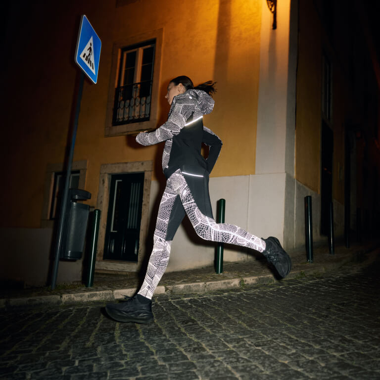 Woman running in the city at night wearing the limited series Akitsu  with reflective Lite-Show LS Top and Lite-Show Tight.