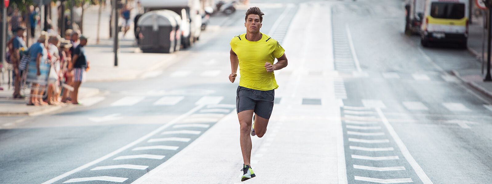 A male runner running down a street in ASICS shoes and clothing