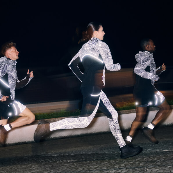 Three runners in the city at night wearing the Akitsu limited series reflective running tops, tights and shorts.