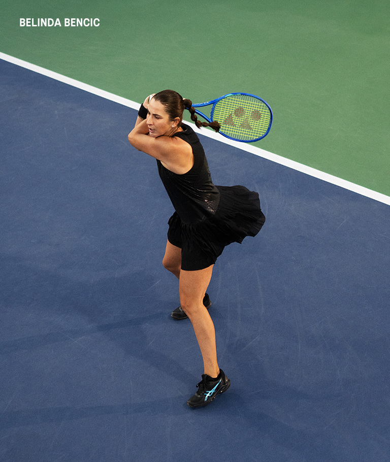 Athlete belinda bencic playing tennis wearing a black dress and black tennis shoes.