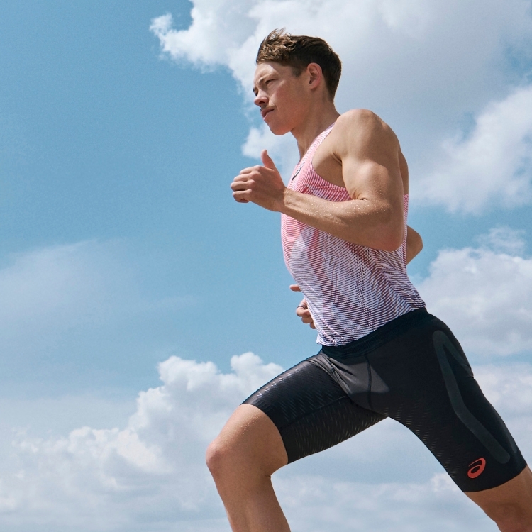 Man running with sky in the background. Wearing a METASPEED running tank top.