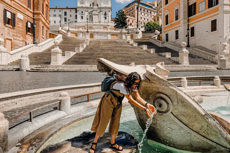 Tourist enjoying the water in the fountain on a sunny day in Rome