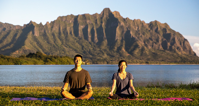 A pair of young adults meditating outdoors