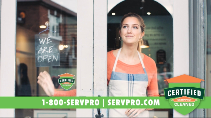 Female store owner in apron looking through store window