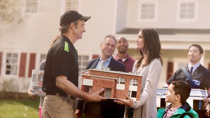 Servpro man handing over a small model house to woman.