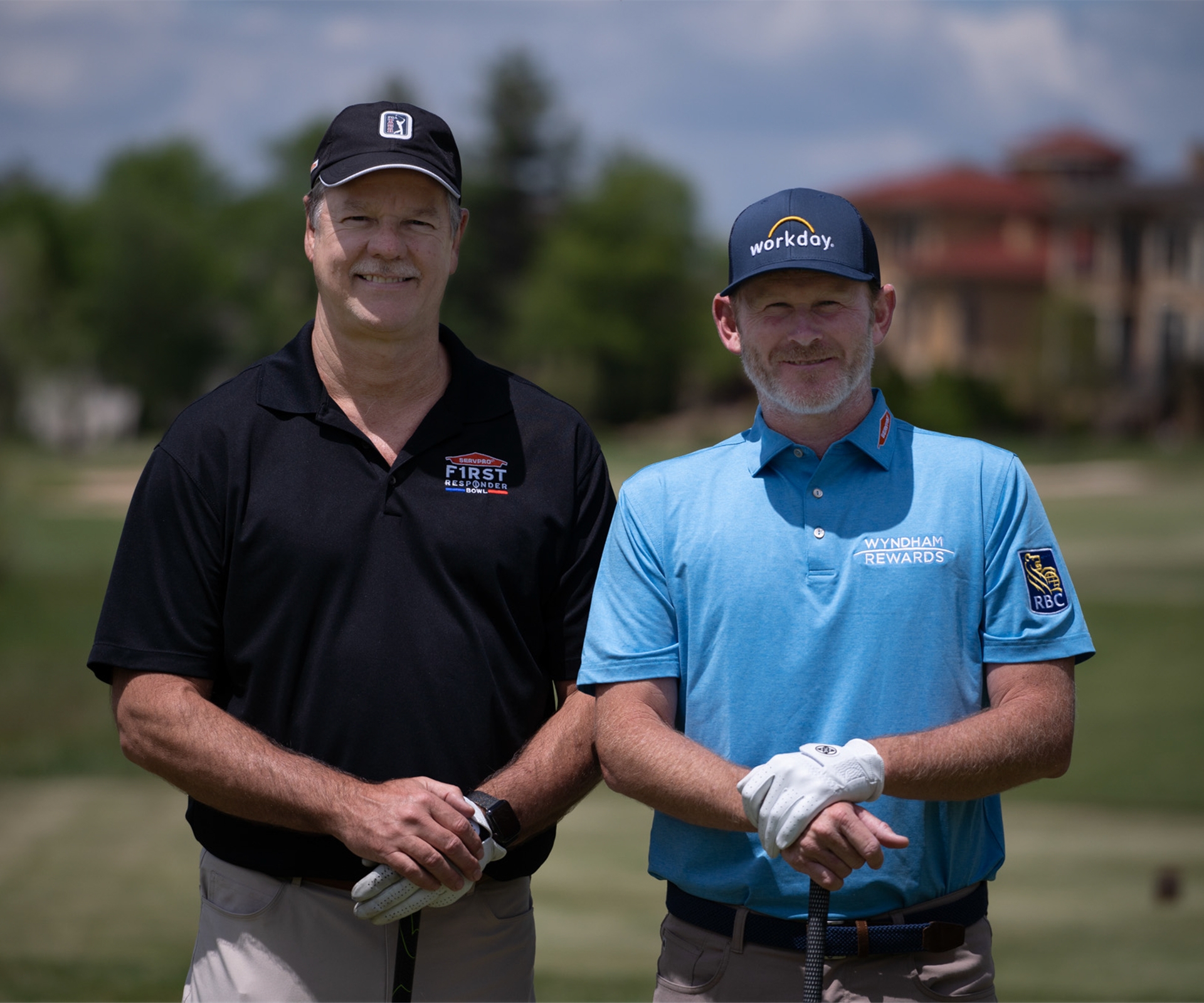 2 men facing the camera with golf clubs in their hands