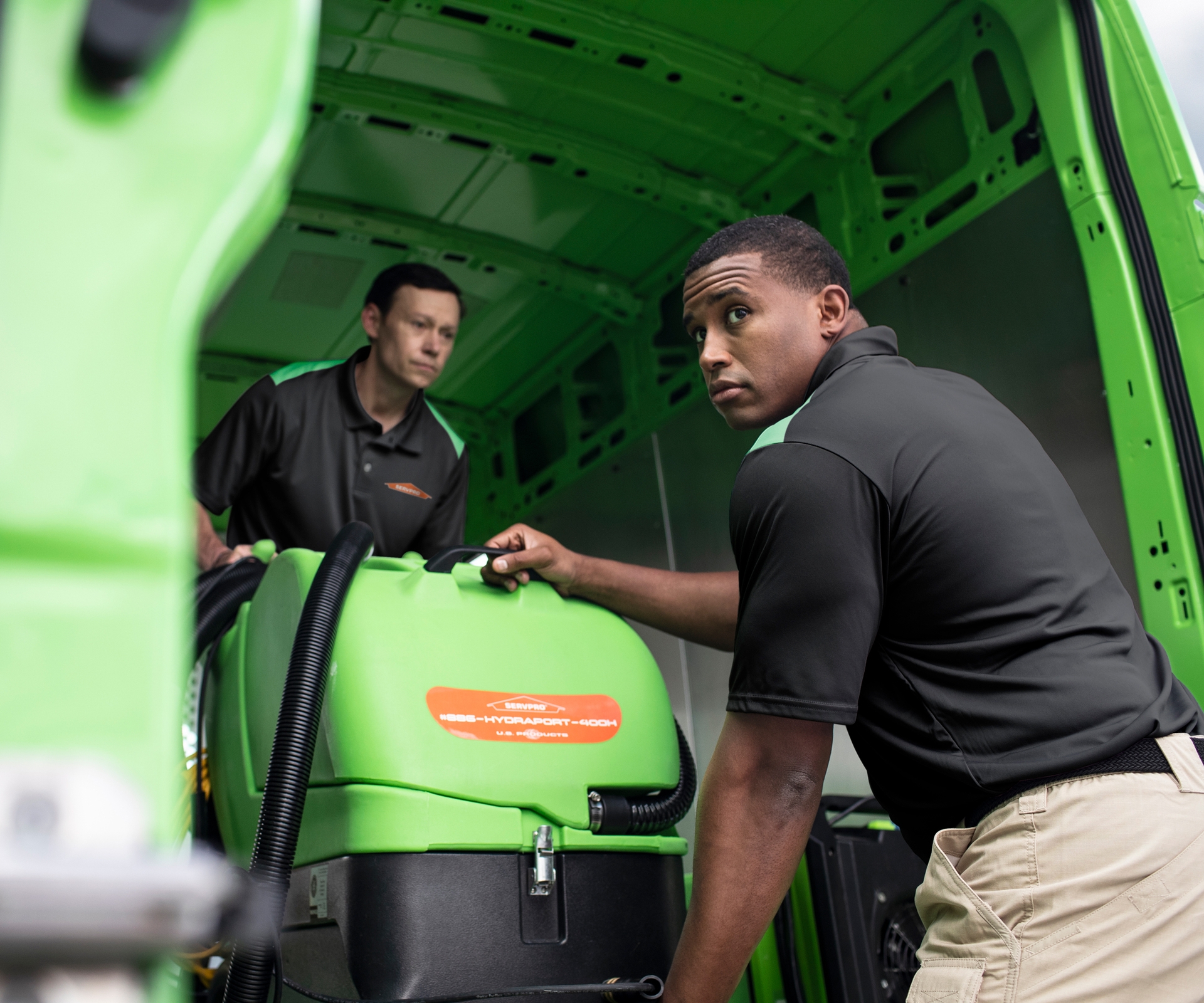 2 SERVPRO employees removing equipment from van