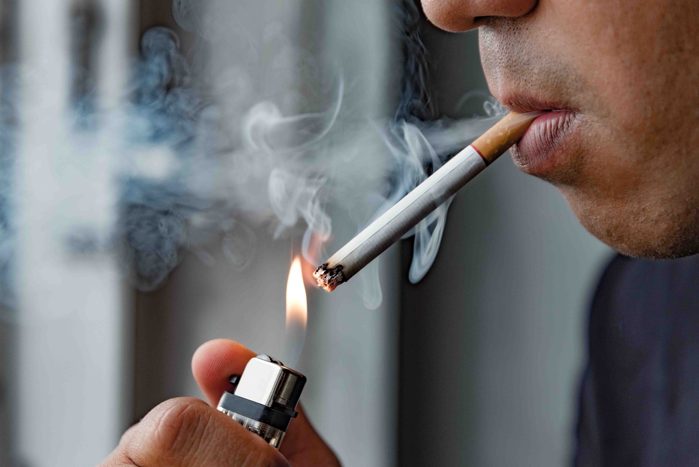 A person lighting a cigarette with a lighter. If you need smoke odor removed from your home or business, call SERVPRO. 