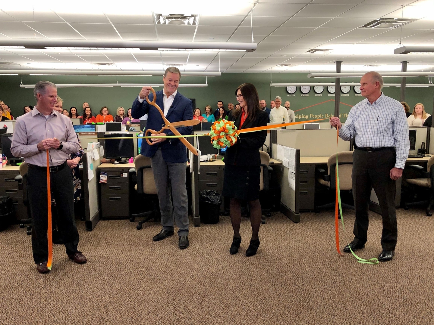 Man cutting ribbon at ceremony inside office