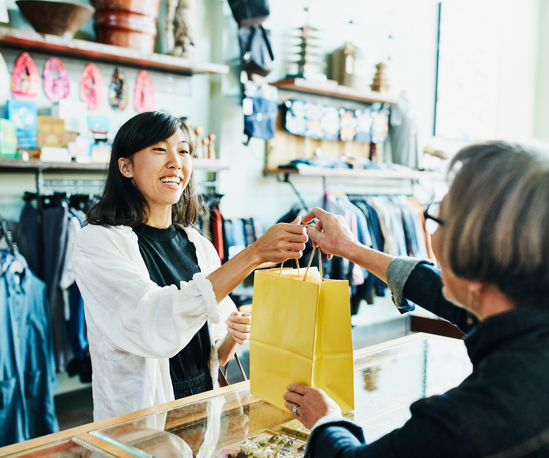 Retail employee handing bag to customer over counter