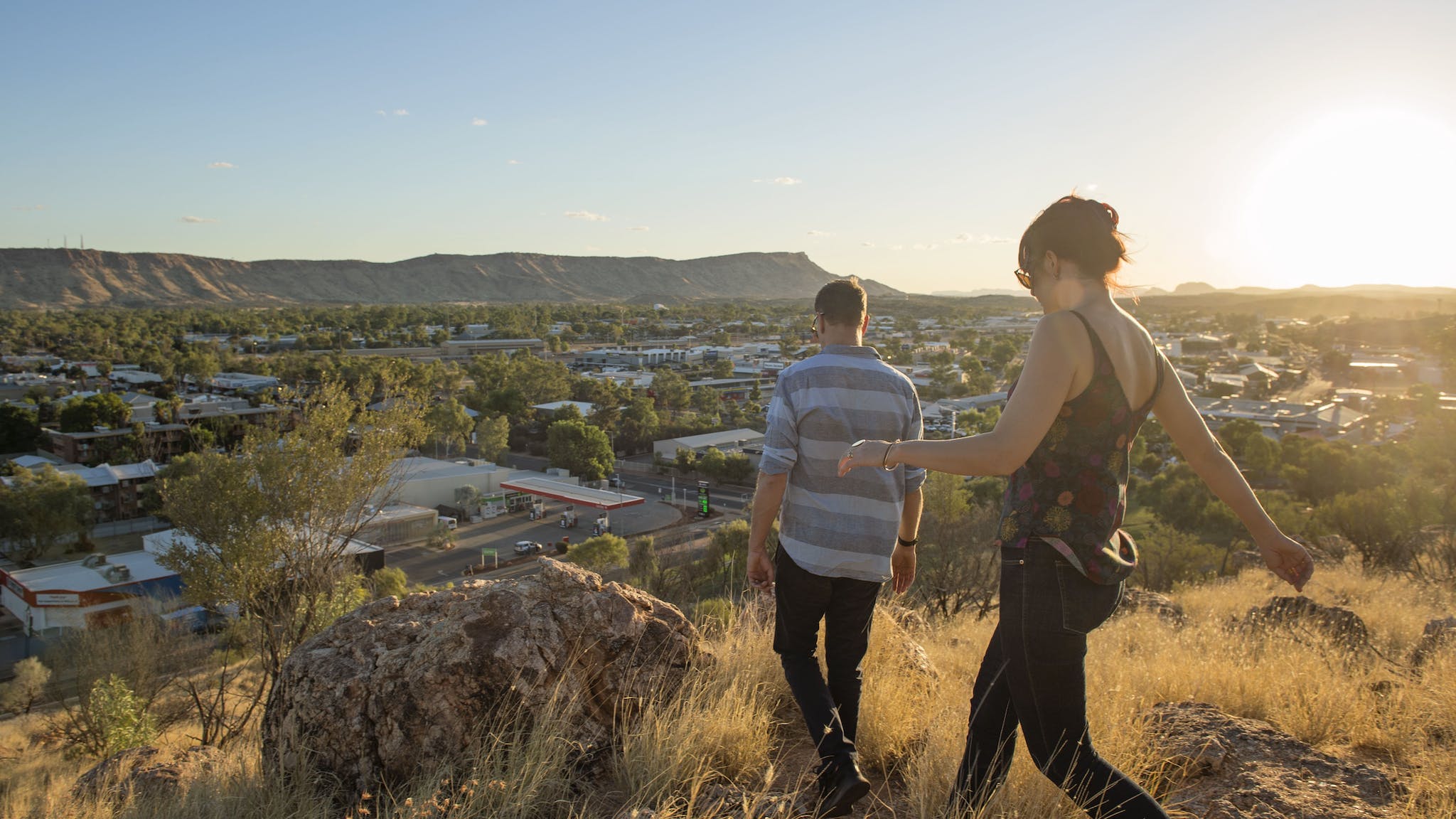 a_couple_walking_on_anzac_hill_overlooking_alice_springs_at_sunset