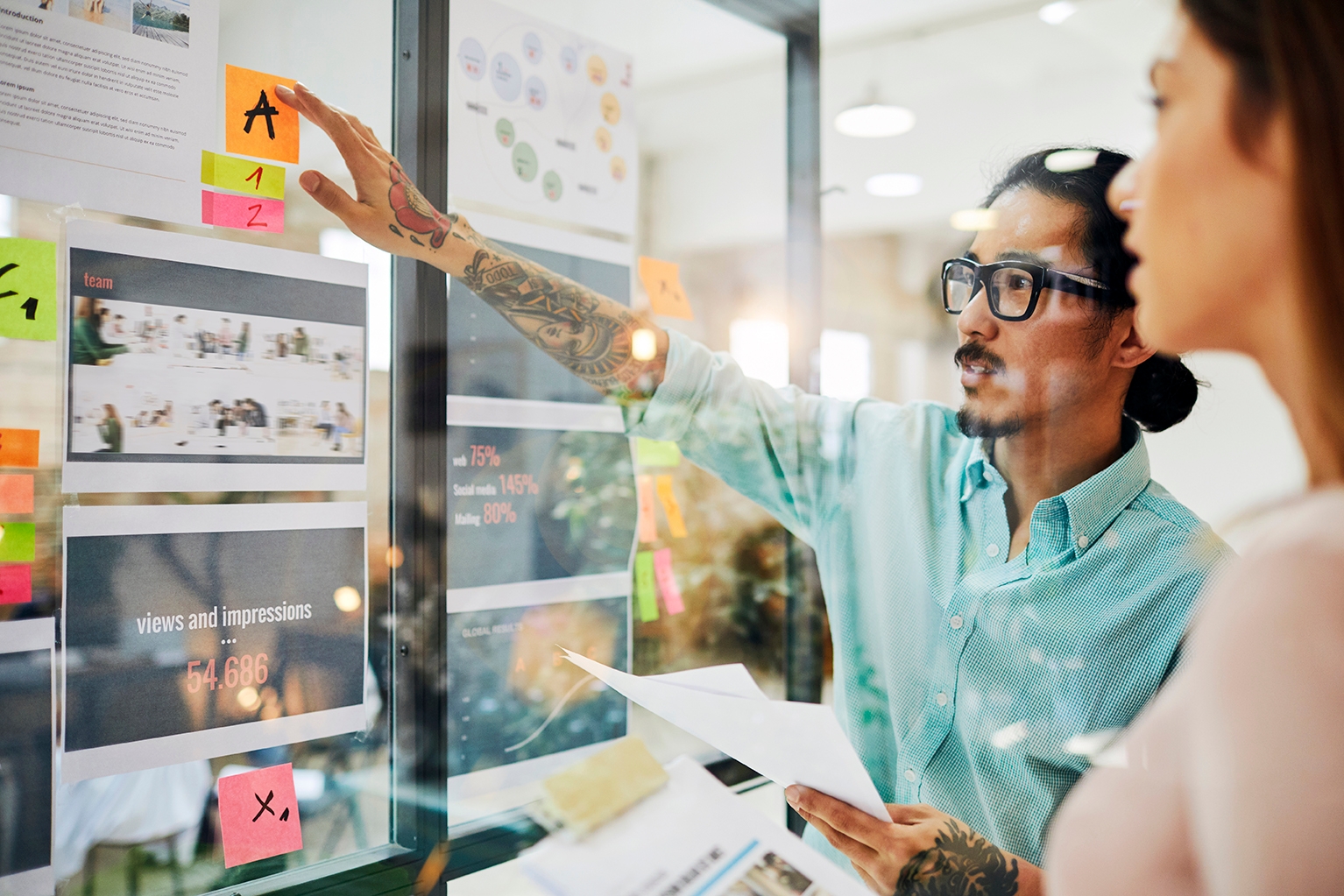 Hombre explicando un proyecto en su oficina a una compañera.