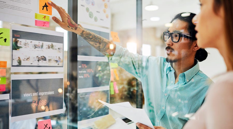 Hombre explicando un proyecto en su oficina a una compañera.