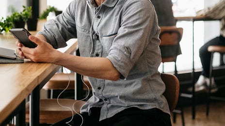 Joven en un café escuchando una clase online de inglés.