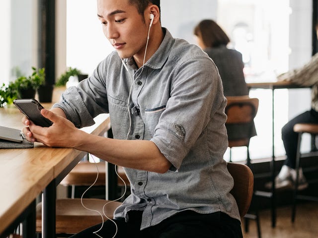 Joven en un café escuchando una clase online de inglés.