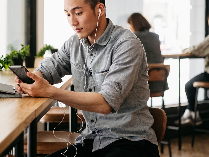 Joven en un café escuchando una clase online de inglés.