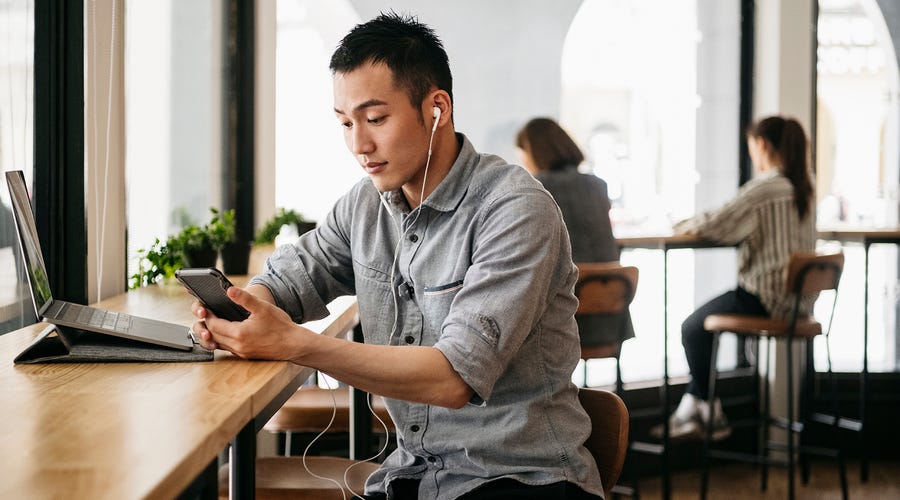 Joven en un café escuchando una clase online de inglés.