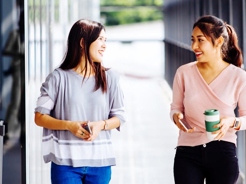 Dos mujeres jóvenes hablando inglés mientras caminan.
