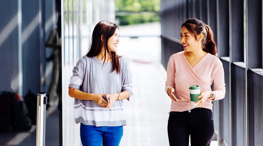 Dos mujeres jóvenes hablando inglés mientras caminan.