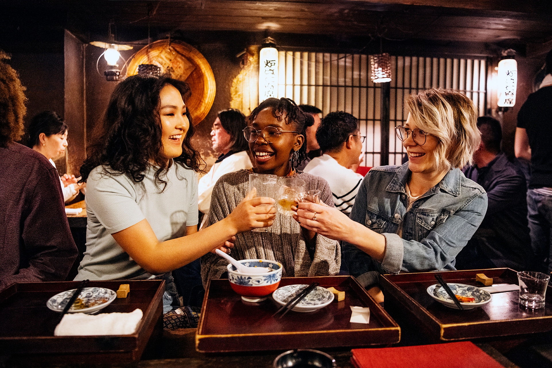 Mujeres haciendo un brindis y teniendo una celebración en un restaurante asiático.