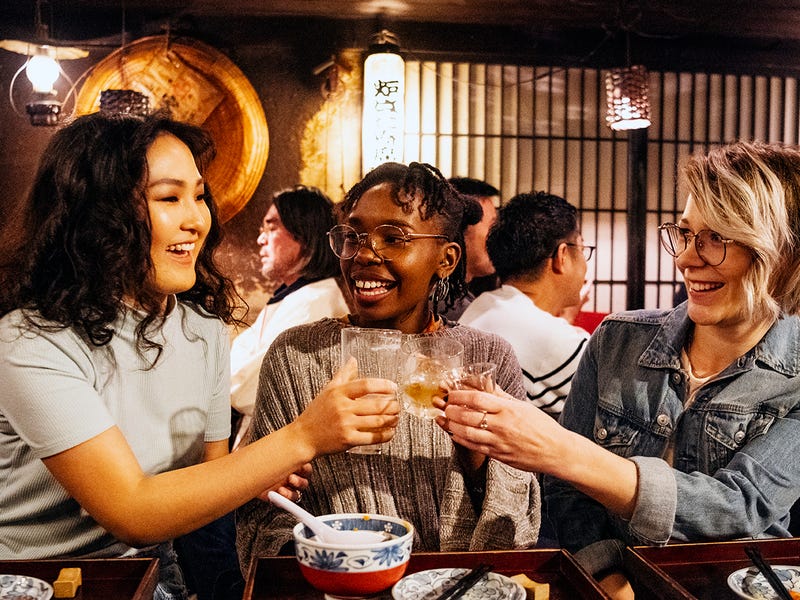 Mujeres haciendo un brindis y teniendo una celebración en un restaurante asiático.