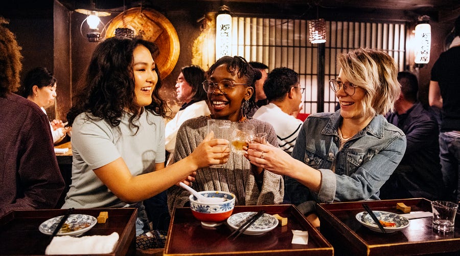 Mujeres haciendo un brindis y teniendo una celebración en un restaurante asiático.