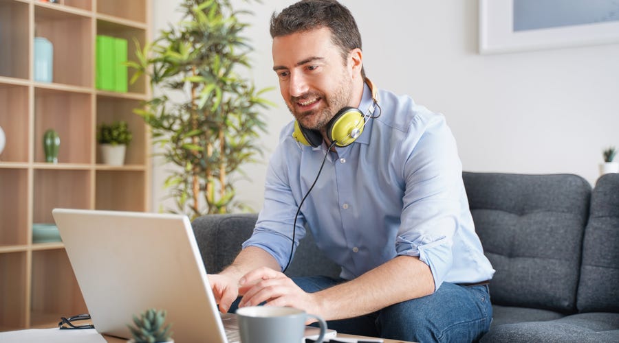 Hombre escribiendo en su computadora un saludo a sus compañeros.