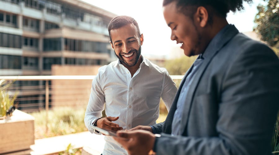 Dos hombres hablando en inglés en un campus universitario.