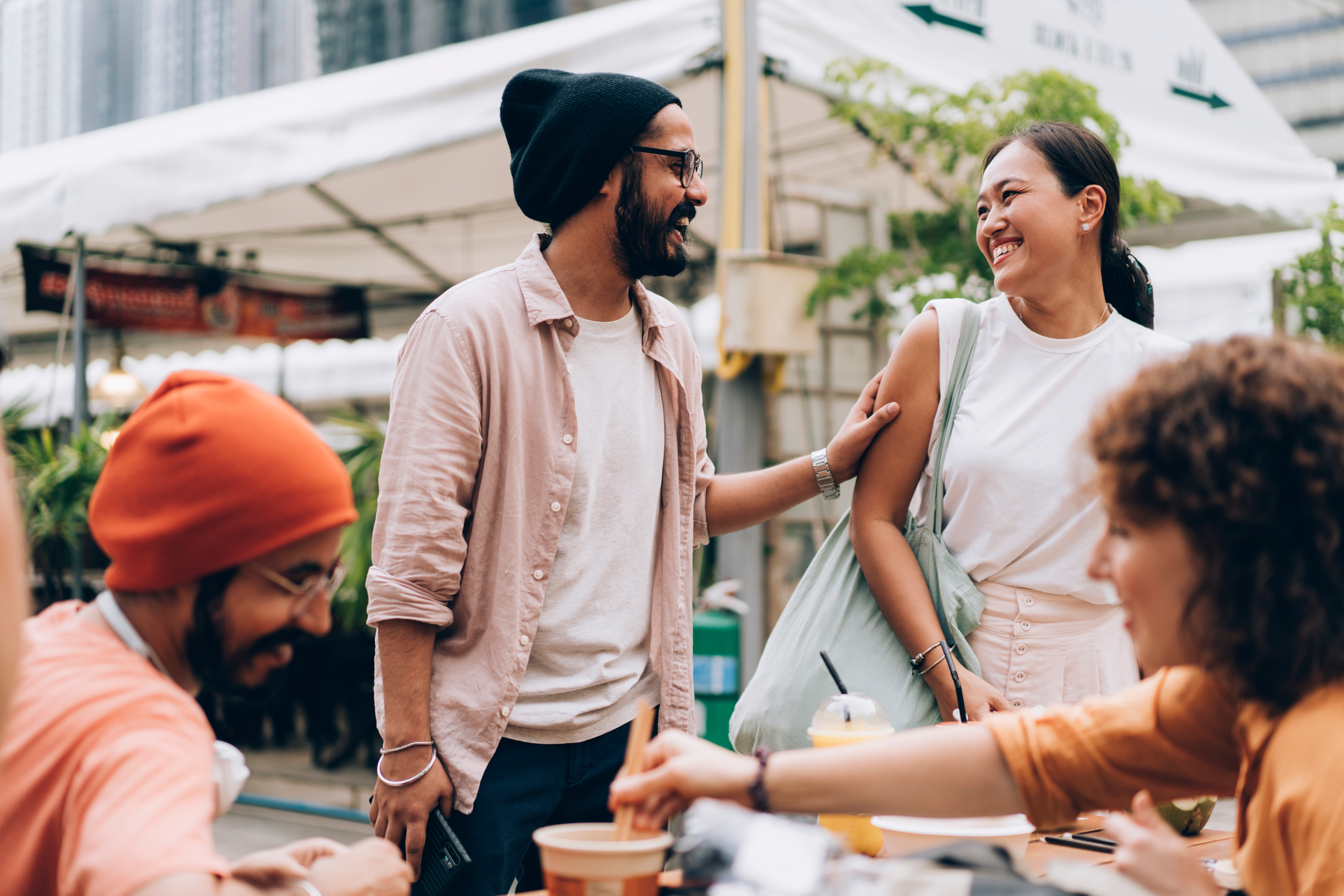 Joven saludando a su grupo de amigos tomando un café en la calle.