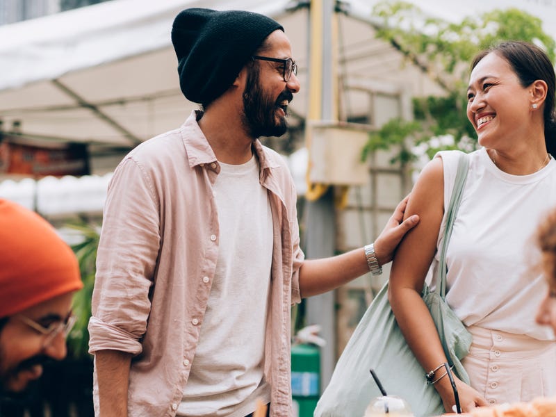 Joven saludando a su grupo de amigos tomando un café en la calle.