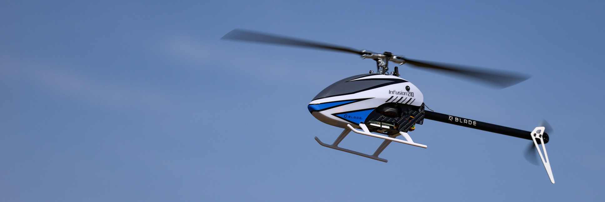 Action shot of the Blade InFusion 210 Bind-N-Fly Basic RC helicopter with AS3X and SAFE hovering in the air above a field Action shot of the Blade InFusion 210 Bind-N-Fly Basic RC helicopter with AS3X and SAFE hovering in the air above a field