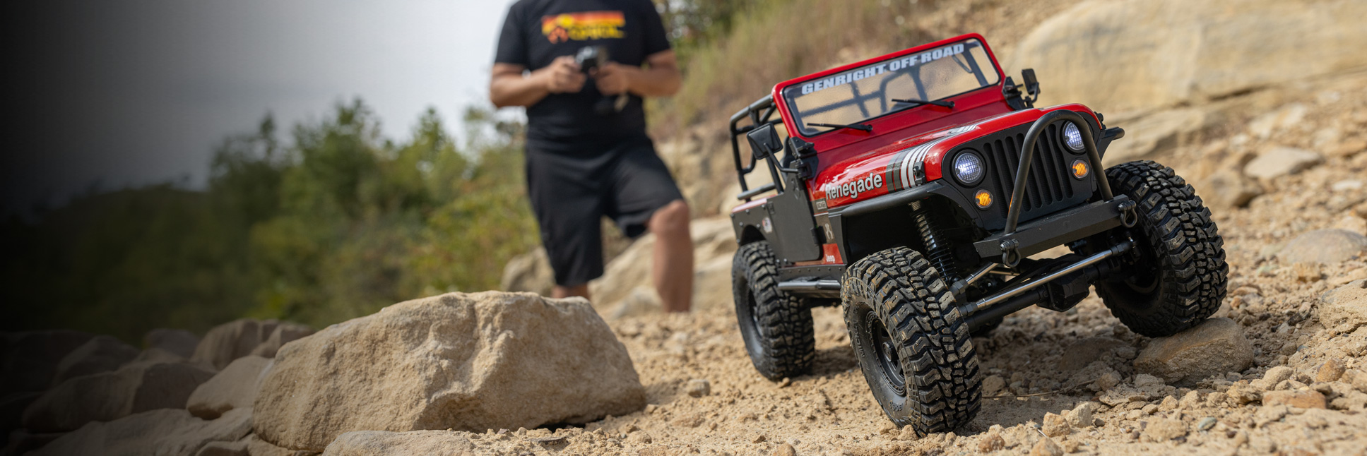 Action shot of the Axial 1/10 SCX10 III Base Camp 4X4 Ready-To-Run Brushed Rock Crawlers in White and Gray climbing over rocks with two people standing in the background holding transmitters in their hands Action shot of the Axial 1/10 SCX10 III Base Camp 4X4 Ready-To-Run Brushed Rock Crawlers in White and Gray climbing over rocks with two people standing in the background holding transmitters in their hands
