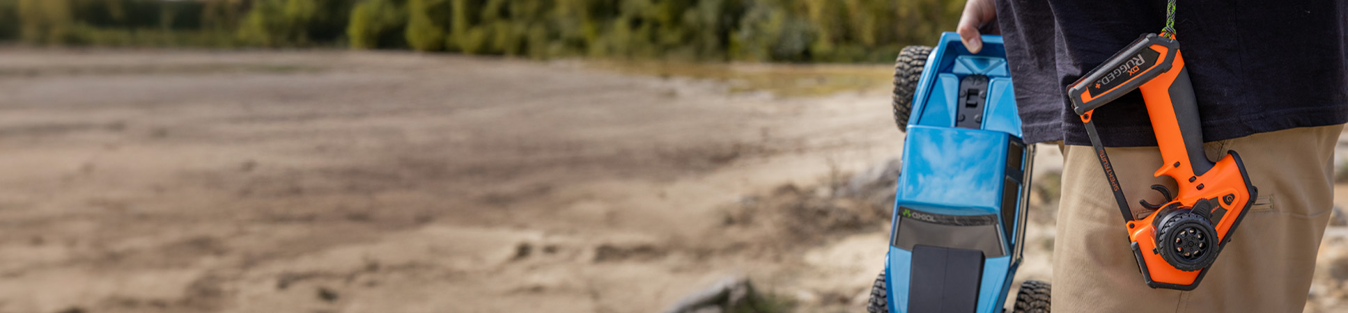 Outdoor lifestyle shot of the Spektrum DX Rugged+ 12-Channel DSMR+ Surface Transmitter, Orange Outdoor lifestyle shot of the Spektrum DX Rugged+ 12-Channel DSMR+ Surface Transmitter, Orange