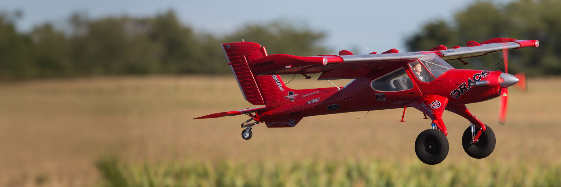 Action shot of the E-flite DRACO 2.0m Smart Bind-N-Fly Basic with AS3X and SAFE Select RC airplane flying through the air above a field Action shot of the E-flite DRACO 2.0m Smart Bind-N-Fly Basic with AS3X and SAFE Select RC airplane flying through the air above a field