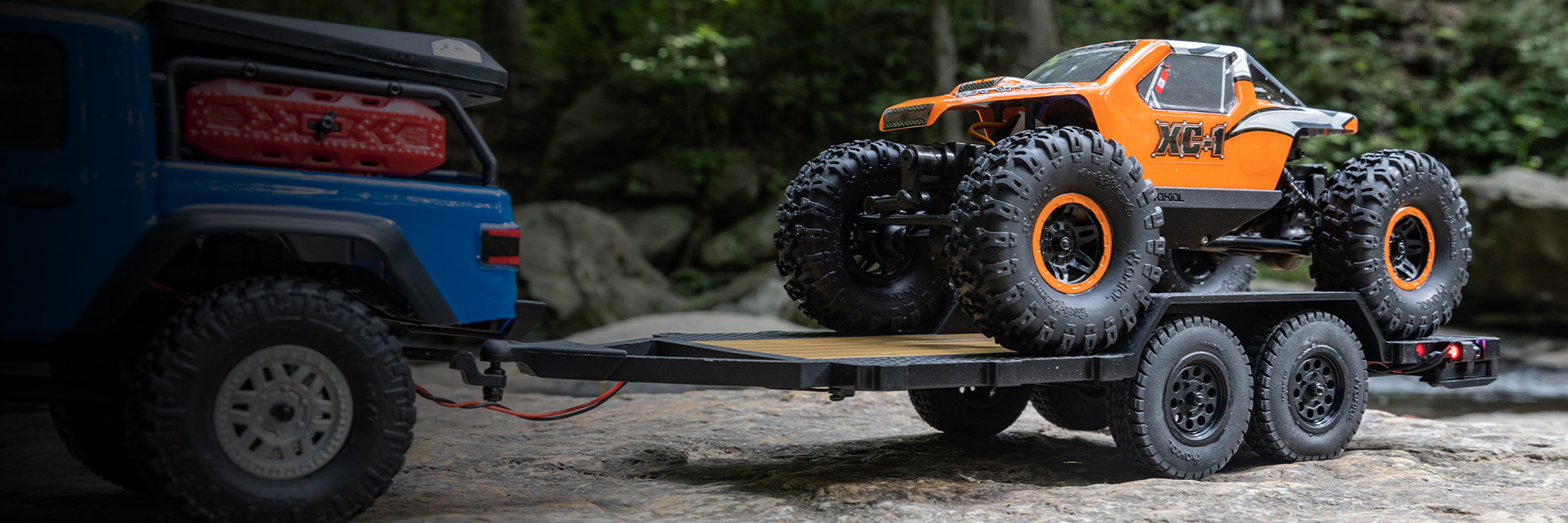 Action shot of an Axial SCX24 pulling the 1/24 SCX24 Flat Bed Vehicle Trailer with the AX24 RC Crawler sitting on top