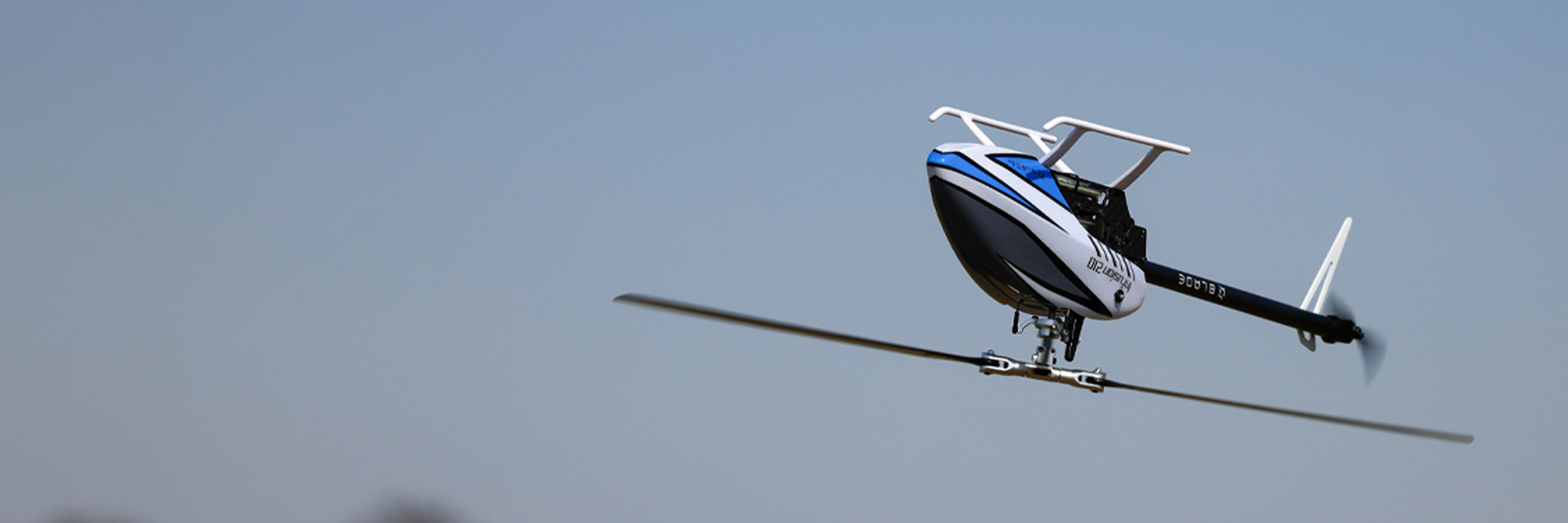 Action shot of the Blade InFusion 210 Bind-N-Fly Basic with AS3X and SAFE RC helicopter hovering in the air above a field