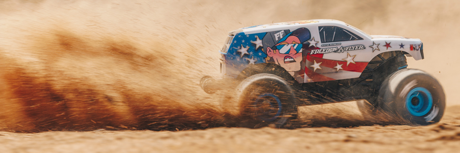 Action shot of the ARRMA Freedom Flyer RC Monster Truck bashing through the dirt with a plume of dust flying in the air Action shot of the ARRMA Freedom Flyer RC Monster Truck bashing through the dirt with a plume of dust flying in the air