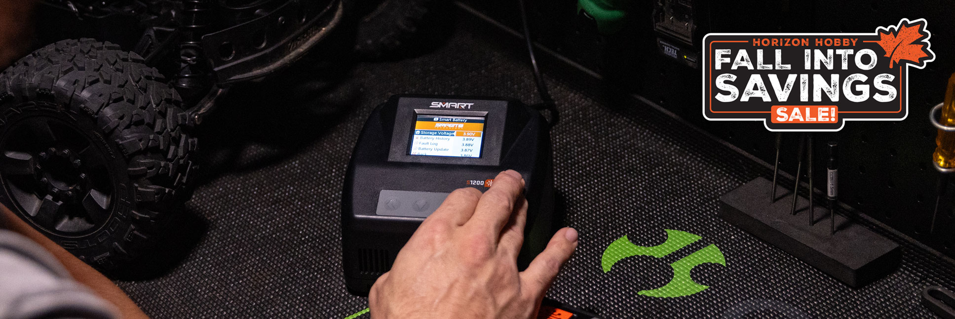 Action shot of the Spektrum S1200 G2 AC 1x200W Smart Charger on a workbench table with the Horizon Hobby Fall Into Savings Logo Action shot of the Spektrum S1200 G2 AC 1x200W Smart Charger on a workbench table with the Horizon Hobby Fall Into Savings Logo