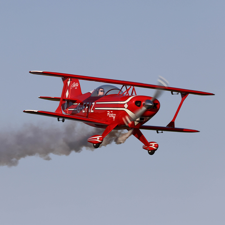 RC Airplane flying through the sky with a smoke trail behind it